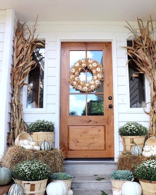 Fall front porch decorated with neutral pumpkins and greenery
