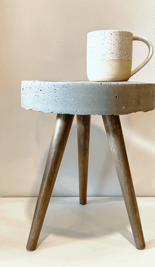 Industrial mid century inspired accent table with a cement top and grey stained wood legs. 