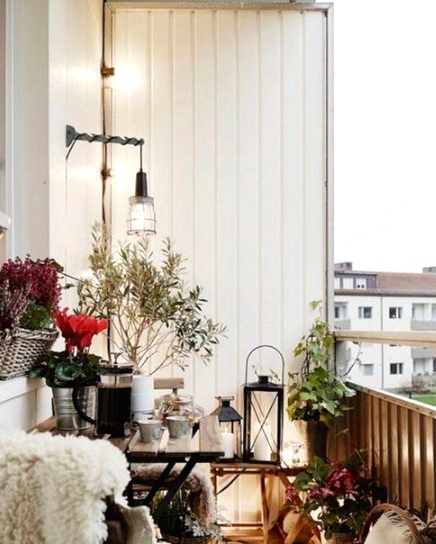 a Christmas balcony with lush bright blooms, greenery in pots, candle lanterns and faux fur here and there