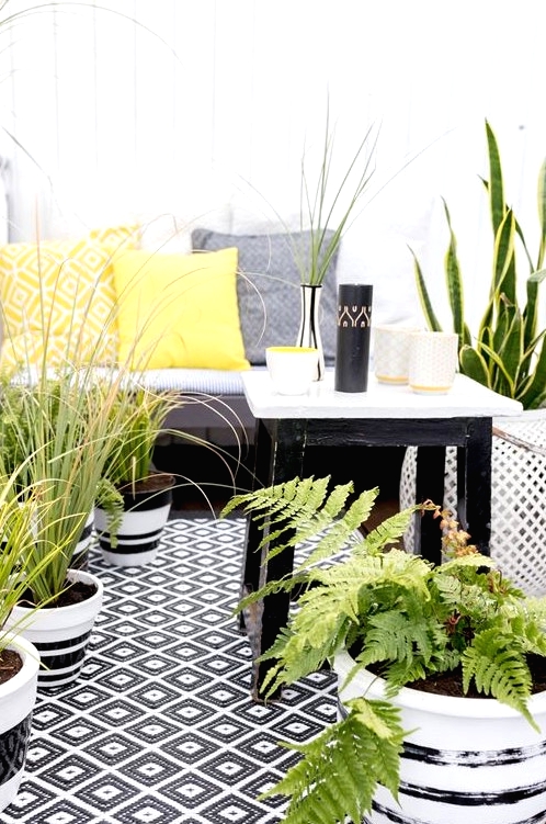 a monochromatic balcony with printed textiles, potted greenery and succulents and simple and stylish furniture
