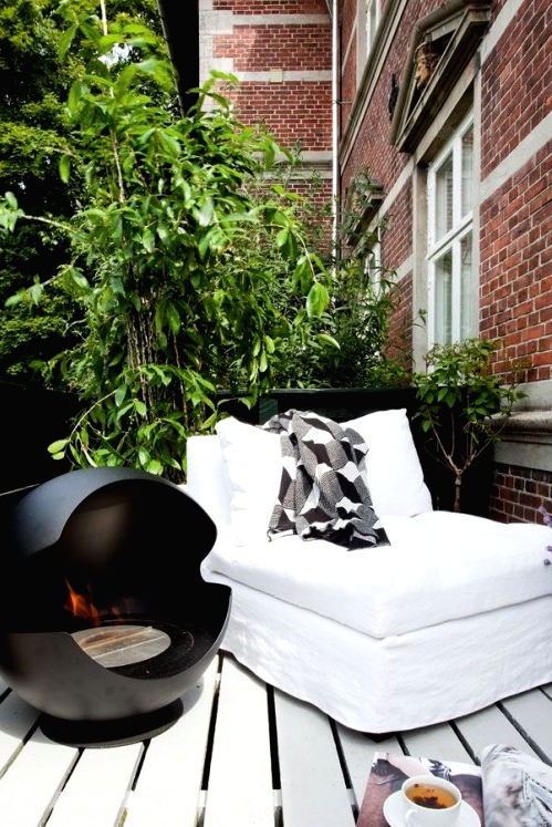 a Nordic balcony with a white lounger, a black open fireplace, lots of greenery around is amazing and relaxing