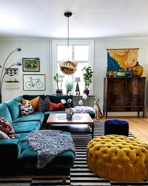 a bright mid-century modern living room with a stained storage unit, a dark green sectional, a yellow ottoman and a navy pouf, colorful pillows and a bold gallery wall