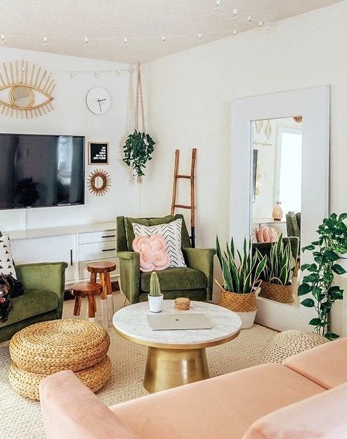 a pretty mid-century modern living room with grene chairs, a blush loveseat, a round table and woven poufs, potted plants and lights