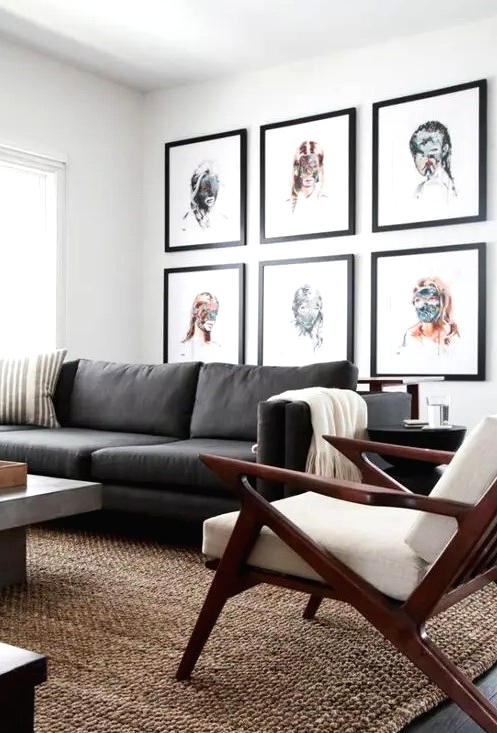 an elegant mid-century modern living room with a grey sofa, a concrete table, a white chair, a bright portrait gallery wall
