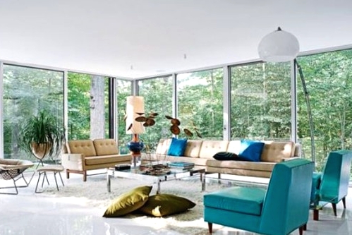 a mid-century modern living room with glazed walls, tan and turquoise seating furniture, a low coffee table and pillows and lamps