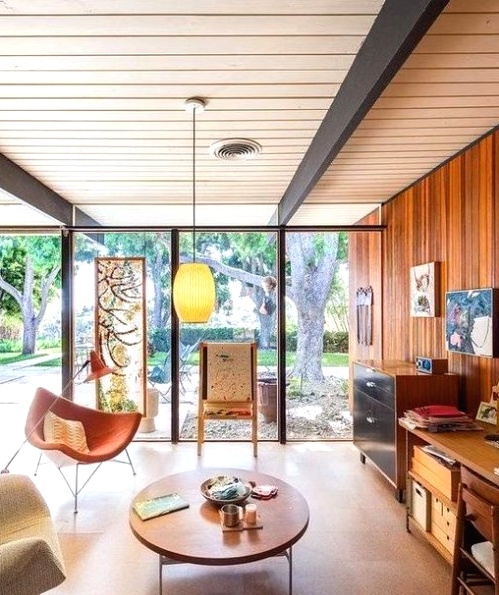 a mid-century modern living room with a wood clad wall and glazed ones, stained storage furniture and seating furniture, a low coffee table, cool artwork