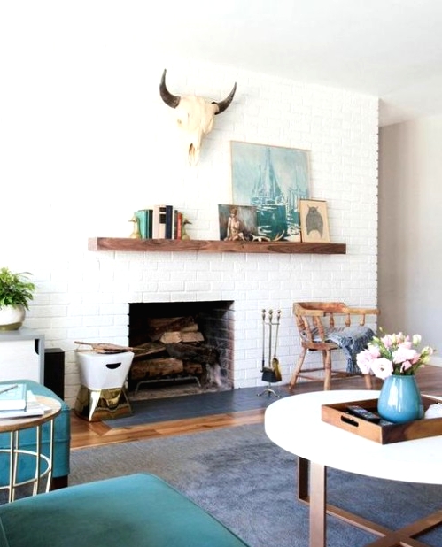 a stylish mid-century modern living room with a white brick fireplace, teal chairs, a round coffee table, some beautiful decor and a skull