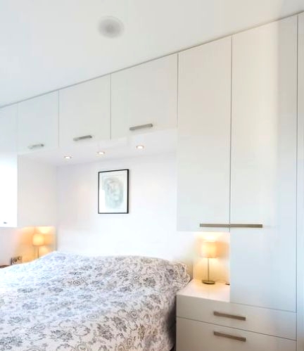 a Scandinavian bedroom with sleek cabinets for storing all the stuff, built-in nightstands and a bed with printed bedding