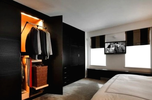 a whole wall taken by black wardrobes with additional light inside are a great alternative to a walk-in clsoet, and they can store no less than such a closet