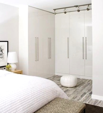 a neutral and stylish bedroom with a whole arrangements of wardrobes forming a personal walk-in closet - that's a very smart and cool idea