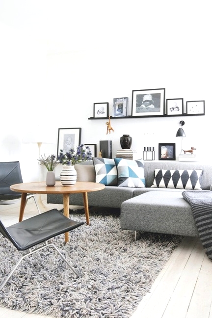 a Scandinavian living room with a grey sectional, black leather chairs, a wooden coffee tables, black ledges for a gallery wall is amazing