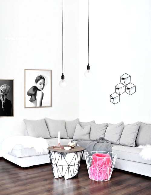 a serene Scandinavian living room with a grey sectional, geometric base coffee tables, pendant bulbs, a geometric sconce with bulbs on the wall