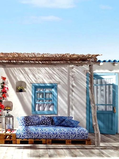 a small Mediterranean outdoor space - a blue printed sofa under a roof, colorful blooms and Moroccan lanterns is amazing