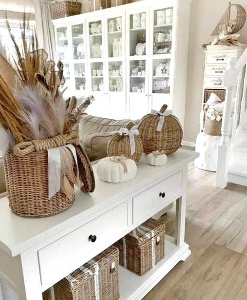 beautiful rustic fall home decor with wicker chests for storage, a basket with grasses, wicker pumpkins and white ones is cool