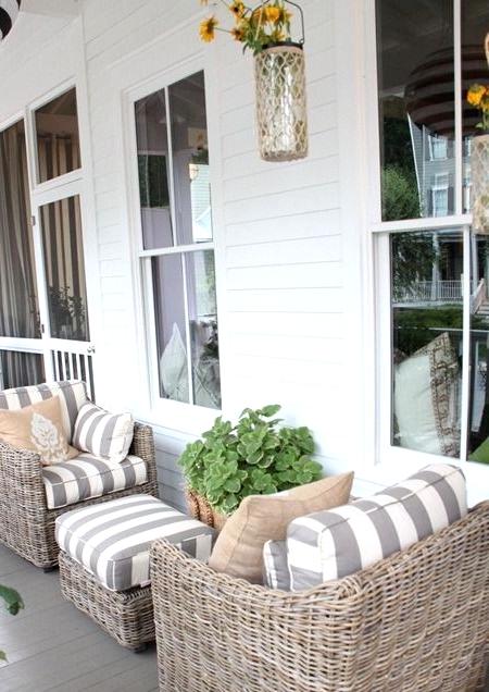 beautiful neutral wicker chairs with striped upholstery, a matching pouf and a basket with greenery for a lovely coastal outdoor space