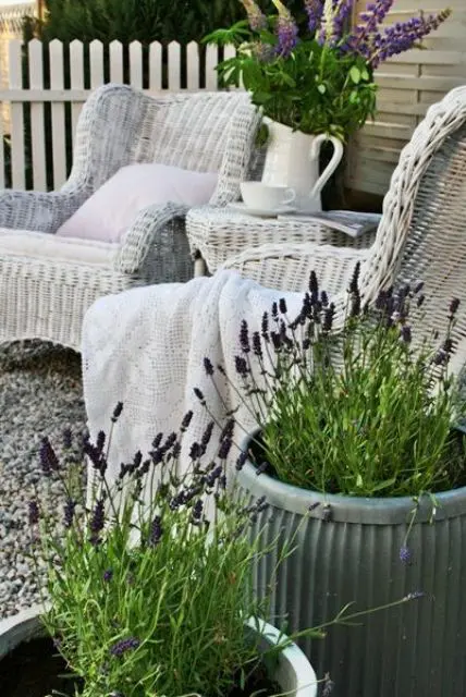 a lovely Provence-inspired with white wicker chairs, a side table, potted lavender, a jug with blooms and greenery