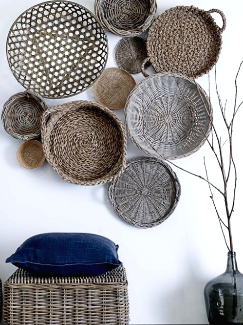 a wicker pouf with a navy pillow, an arrangement of decorative baskets and wicker plates for giving a rustic feel to the space