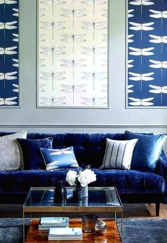 a living room with an electric blue sofa, printed pillows, a gallery wall of wallpaper, a tiered coffee table and a midnight blue rug