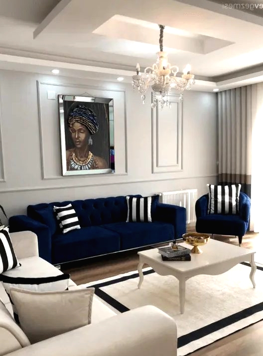 a neutral living room with a navy sofa and chair, a creamy sofa, a vintage coffee table and striped pillows and a rug plus a chic crystal chandelier