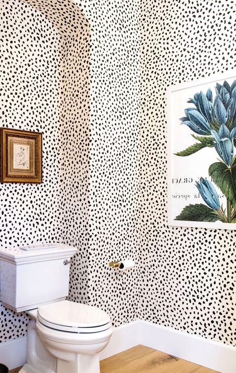 a pretty bathroom with Dolmatin walls, a blue floral artwork, a small vintage one and gold touches is a stylish space