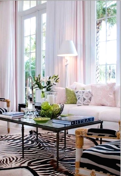 an elegant living room with a creamy sofa and pastel pillows, a black coffee table, zebra print chairs and a rug and some greenery to refresh the space