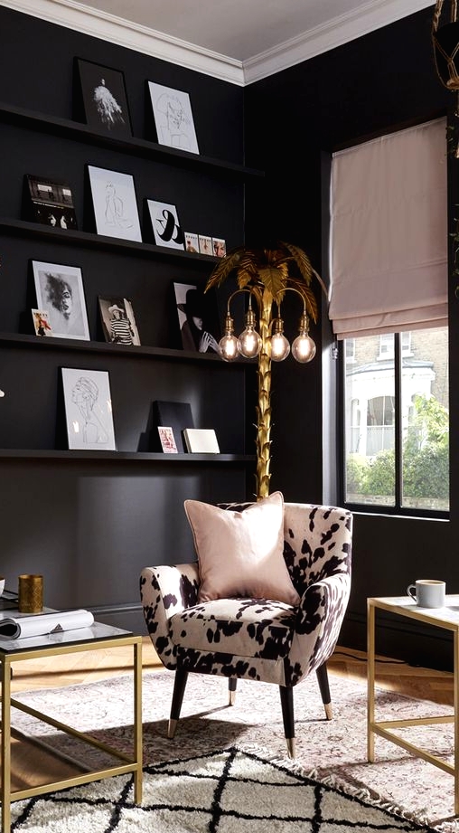 an urban glam living room with matte black walls, an animal print chair, gold frame coffee tables, a gold tree-like floor lamp