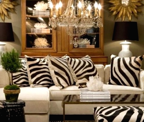 an elegant art deco living room with a white sectional, zebra print pillows, a glass cabinet for storage and a crystal chandelier plus black lamps