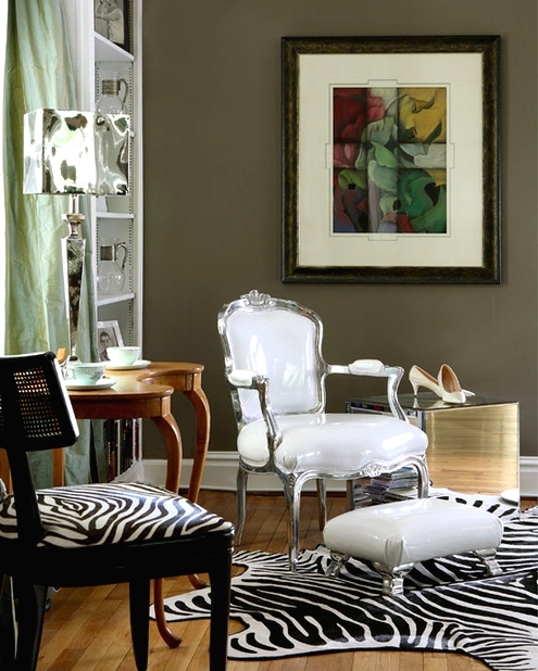 taupe walls, a vintage white chair and a zebra print one, a vintage table, a zebra print rug and a white footrest for a bold look