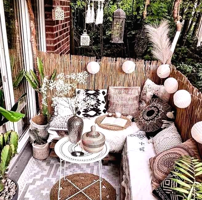 a gorgeous boho balcony with layered rugs, a corner pallet sofa with lots of boho pillows, Moroccan lanterns, lights and potted greenery is amazing