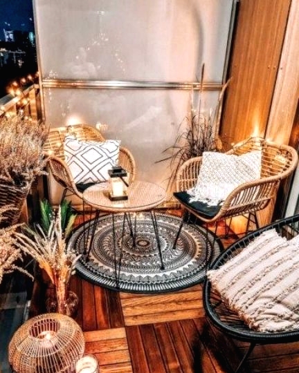 a modern meets boho balcony with rattan furniture, a cane coffee table, various grasses in baskets and vases, candle lanterns and lights
