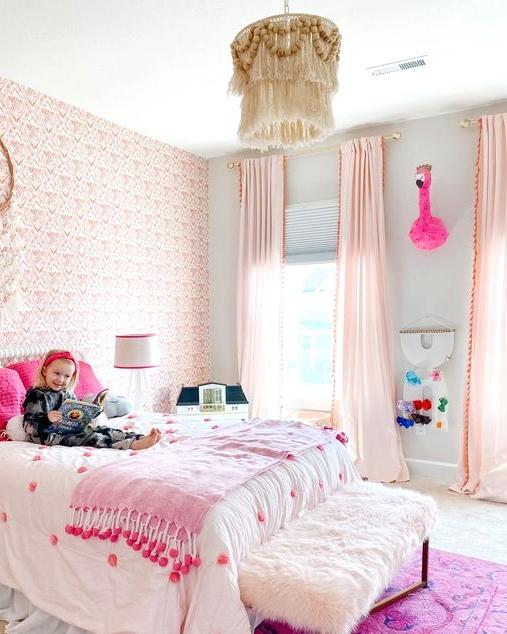 a fantastic pink boho girl's bedroom with a pink wallpaper wall, light pink curtains, a bed with hot pink pillows and a hot pink rug