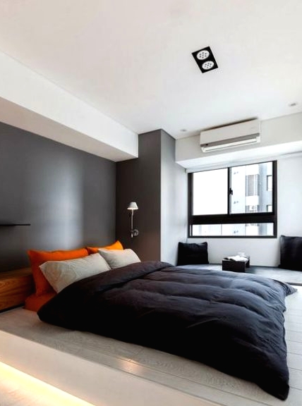 a minimalist bedroom with a grey accent wall, a platform bed with built-in lights, lamps and black and bright textiles