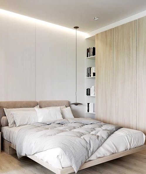 a cozy minimalist bedroom with a raised bed with an upholstered headboard, a sleek storage unit and pendant lamps