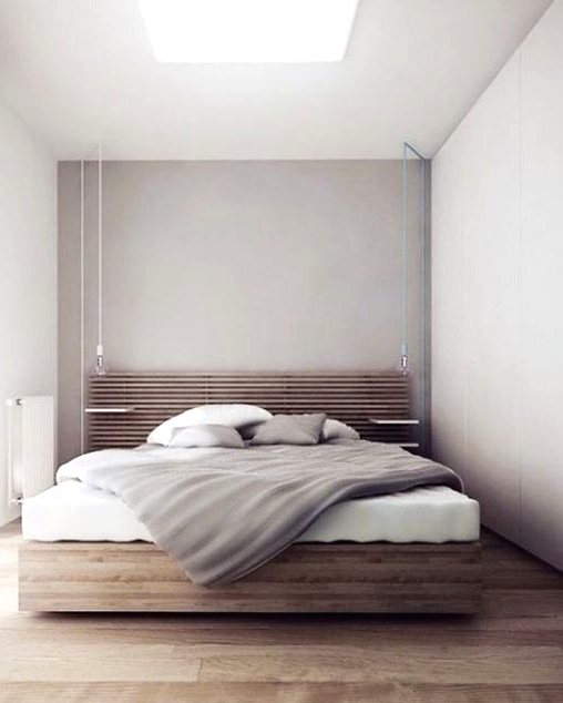 a minimalist bedroom with dove grey walls and a skylight, a stained bed with a slab headboard, neutral bedding and much light