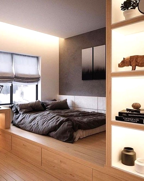 a minimalist bedroom with a platform bed with storage, lit up niches for storage, a built-in desk and a black chair