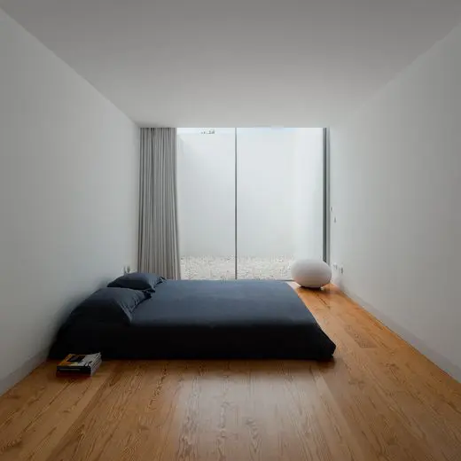 an ultra-minimalist bedroom with a glazed wall, a low bed with black bedding, a pouf and nothing else is pure zen and relaxation