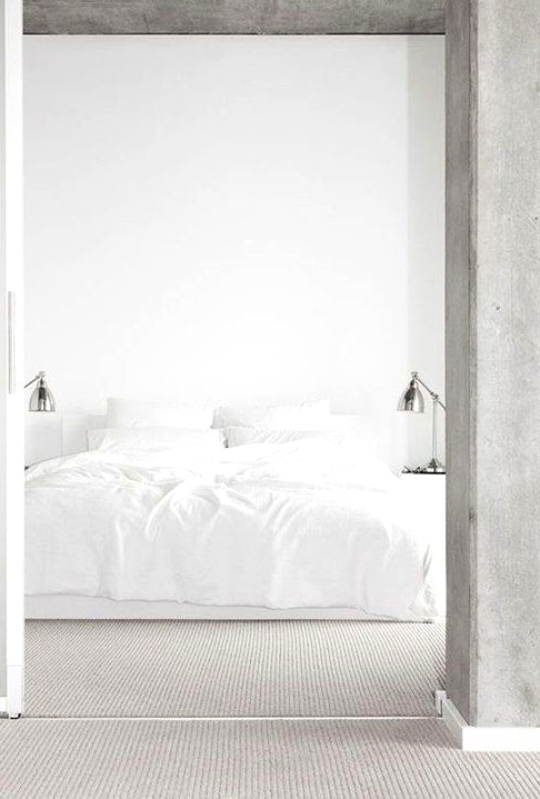 a white minimalist bedroom with a concrete ceiling, a bed with white bedding and metal table lamps is amazing