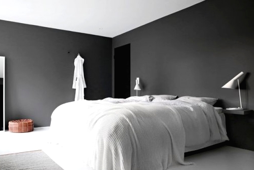 a moody minimalist bedroom with black walls, a white bed with bedding, black nightstands and white table lamps