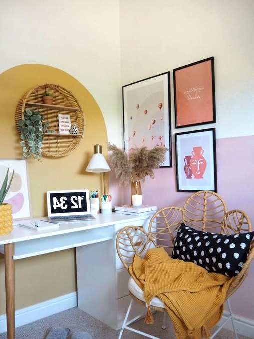 a small nook turned into a working space, with a modern desk, shelves, a gallery wall, a round rattan shelf, potted plants and a lovely papasan chair