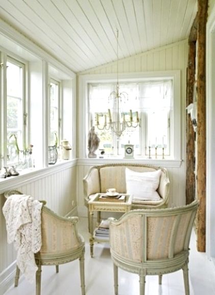 a vintage neutral Scandinavian sunroom with sophisticated furniture, vintage chandeliers, neutral textiles