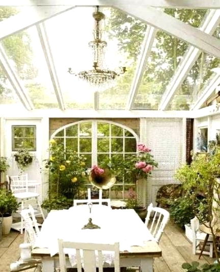 a vintage Scandinavian sunroom with lots of greenery and bold blooms, white vintage furniture, a crystal chandelier