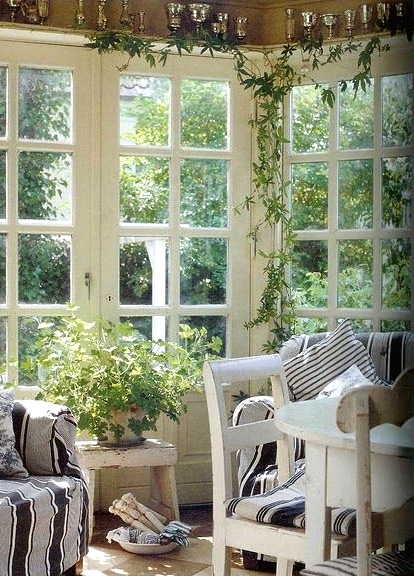 a vintage Scandinavian sunroom with striped black and white vintage furniture, potted greenery and lots of sunlight coming in