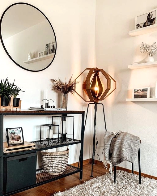 a modern metal and wood console table, potted plants, grass in a vase, some candleholders, a box and a basket plus a very eye-catchy floor lamp