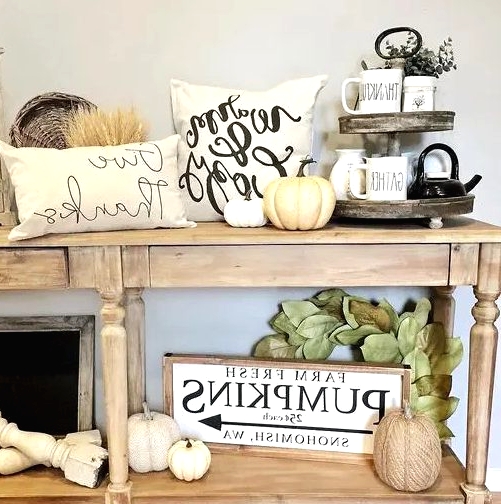 a neutral fall console table with white natural and faux pumpkins, wheat, leaves and printed pillows