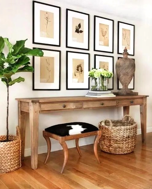 a summer console with baskets around, a wooden sculpture, greenery and vintage botanical artworks