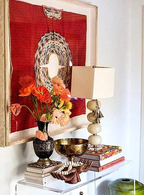 an acrylic console table with a bold artwork, bright blooms, some finds from trips, bright blooms in a vintage vase for an inspiring entryway