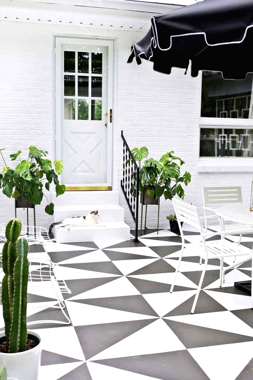a black and white patio with a tiled floor, white dining furniture and a black umbrella, potted greenery and cacti
