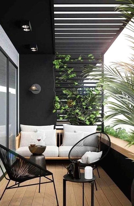 a chic balcony with black walls, a neutral sofa, black chairs and a tiny table plus lots of greenery