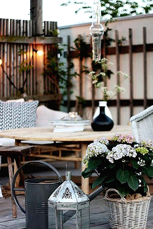 a Scandinavian terrace with rattan furniture, wicker chairs, potted plants and watering cans