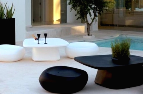 an ultra-minimalist outdoor space with minimal black and white low coffee tables and stools is a bold and catchy space